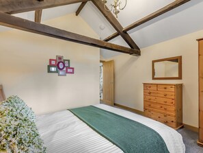 Un dormitorio con cama, cómoda, espejo y un adorno en la pared.
