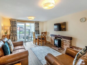 Una sala de estar con sofás de cuero, chimenea, televisor de pantalla plana y comedor con mesa y sillas.