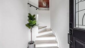 A staircase with white walls, a potted plant, and a door with a glass panel. - Luxury 3 BDRM Home In Toronto Ontario (Toronto)