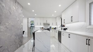A modern kitchen with white cabinetry, a marble island, and a sleek design. - Luxury 3 BDRM Home In Toronto Ontario (Toronto)