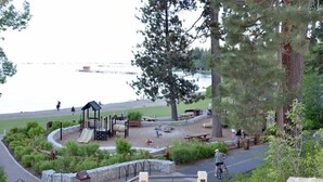 Un parc amb zona de jocs, taules de pícnic i vista a l'aigua.