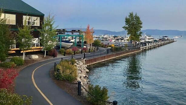 Una propietat amb vistes al mar, un passeig pavimentat, un moll i un port esportiu al fons.
