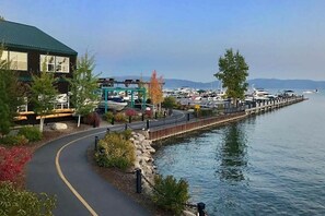 A waterfront property with a paved walkway, a dock, and a marina in the background.