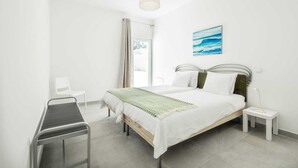 Un dormitorio moderno con una cama, mesitas de noche, un escritorio y una ventana con cortinas.