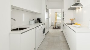 Una cocina moderna con armarios blancos, lavadora integrada y una zona de comedor con mesa y sillas.