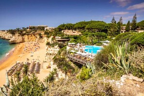A coastal resort with a beach, a pool, and lush greenery.