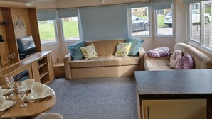 A cozy RV interior with a sofa, dining table, and kitchenette. - Beautiful Caravan Phoenix In St Margaret's Bay. Pet Friendly (Saint Margaret's at Cliffe)