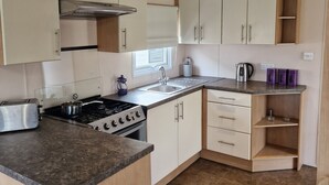 A compact kitchen with a gas stove, a toaster, and a sink. - Beautiful Caravan Phoenix In St Margaret's Bay. Pet Friendly (Saint Margaret's at Cliffe)