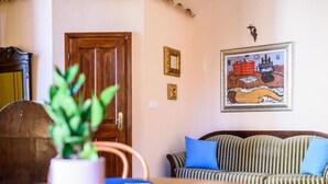 Un comedor con una mesa de madera, sillas, una planta en maceta y un sofá a rayas con cojines azules.