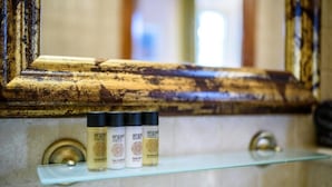 Un baño con un espejo, una repisa y tres botellas de aceite de argán.