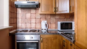 Una cocina compacta con armarios de madera, cocina a gas, horno y microondas.