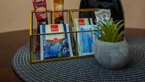 Una mesa con una vitrina de vidrio que contiene varios productos envasados, una planta en maceta y un florero negro con ramas de junco.
