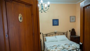Un dormitorio con una puerta de madera marcada con el número 4, una cama con ropa de cama floral, un candelabro y una mesita de noche pequeña.