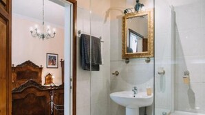 A modern bathroom with a glass shower enclosure, a white bathtub, and a wooden vanity.