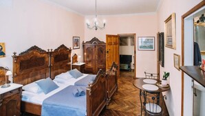 A bedroom with a wooden bed, a small round table with chairs, a mirror, and a chandelier.