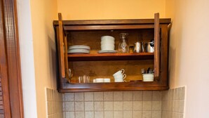 Una cocina compacta con un lavamanos, estufa y un estante de madera encima.