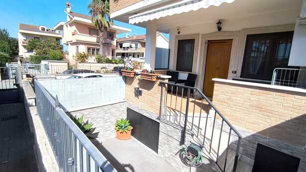 Un edificio residencial con balcón, un pequeño jardín y fachada de ladrillo.