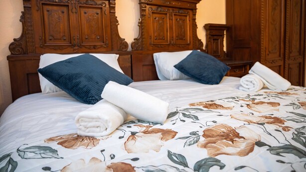 Una cama bien hecha con ropa de cama floral, dos almohadas y un cabecero de madera.