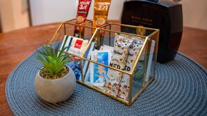 Una cafetera, una planta en maceta y un soporte para cápsulas de café sobre una mesa.