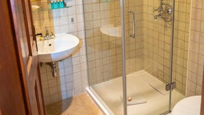 Un baño moderno con ducha de vidrio, lavabo blanco y retrete.