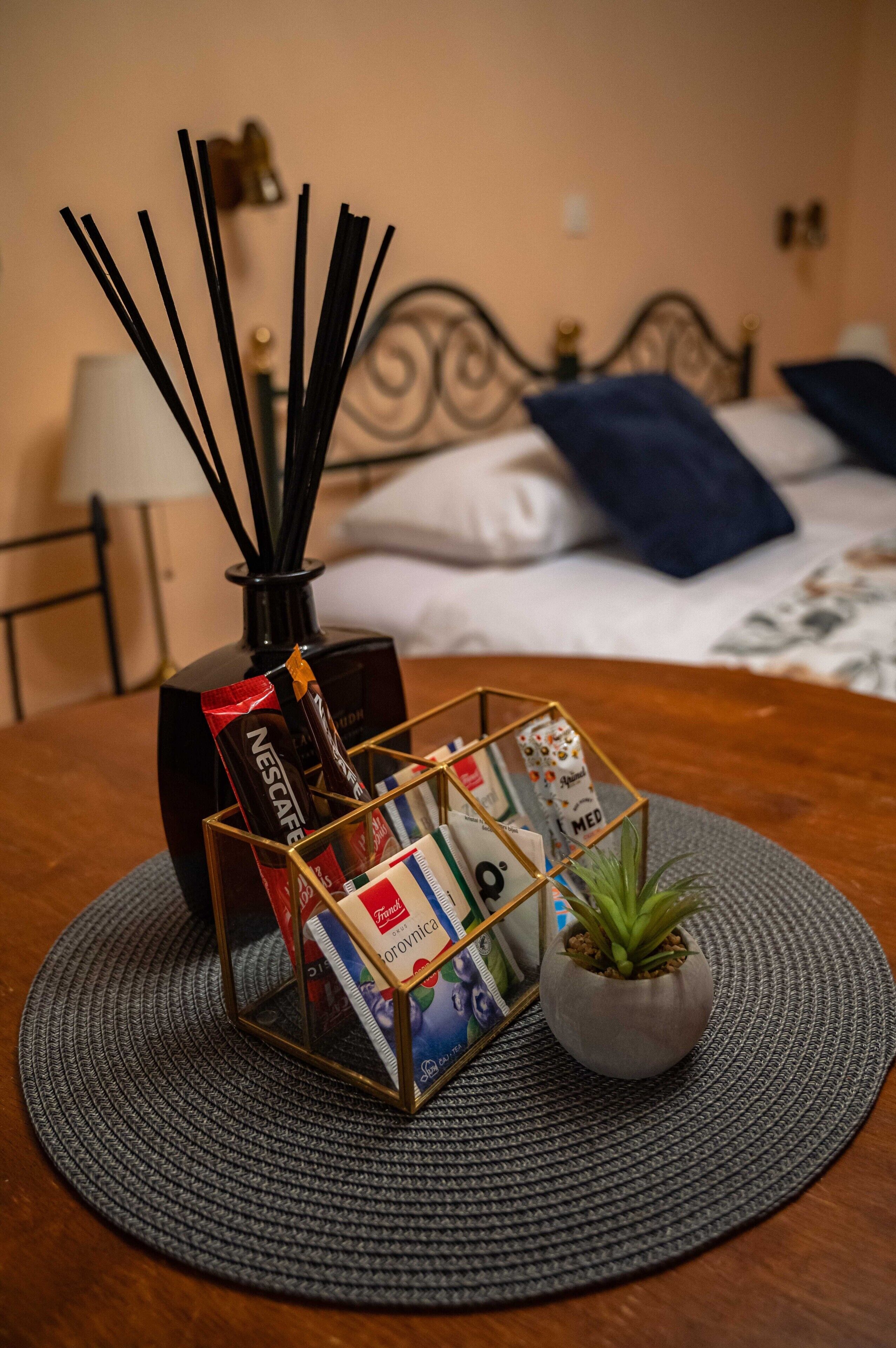 Una mesa ordenada con un atril para revistas, una pequeña planta en maceta y una cafetera Nescafé.