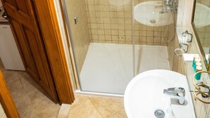 A bathroom with a shower, a sink, and a mirror.