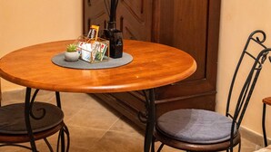 A dining area with a round wooden table, two chairs, a cabinet, and a small plant on the table.