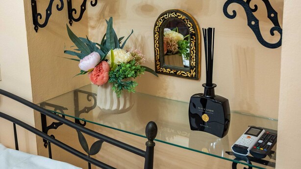 Une pièce comprenant une table en verre sur laquelle sont exposés des objets décoratifs, un lit avec un oreiller blanc et une balustrade en métal.