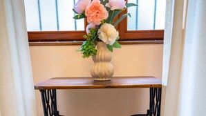 Une table ancienne pour machine à coudre Singer, sur laquelle est posé un vase de fleurs.