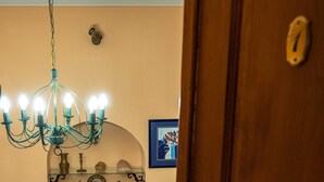 Une chambre à coucher avec un lit, une petite table, une chaise, un lustre et une porte.