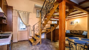 A kitchen with a built-in stove, a wooden staircase with a wrought iron railing, and a dining area with a table and chairs.