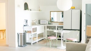 A modern, well-lit living room with a sofa, a coffee table, and a dining area with chairs and a small table. - Bosch Huis Sea: The Garden Suite (Savannah)