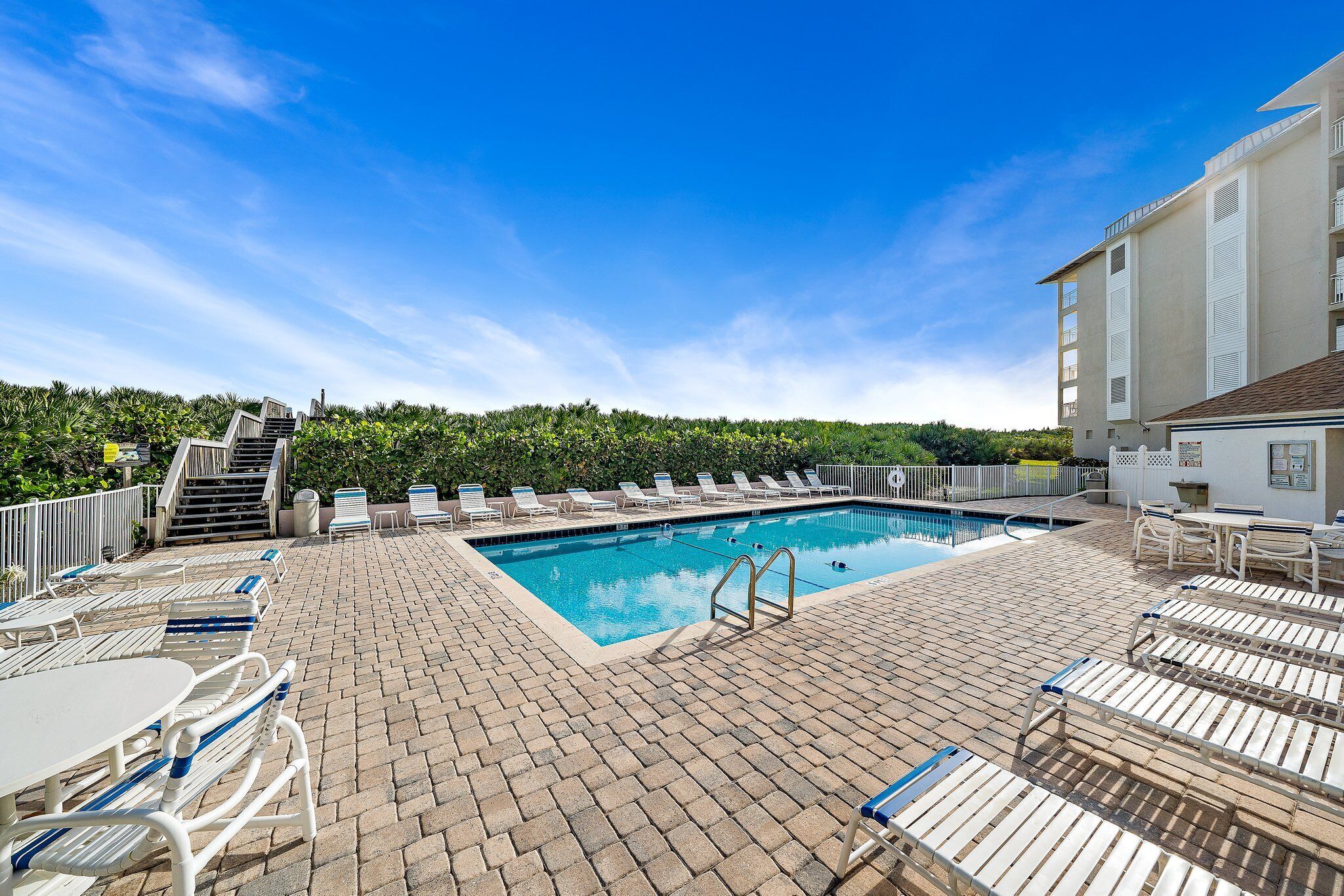 A swimming pool with lounge chairs and a brick patio.