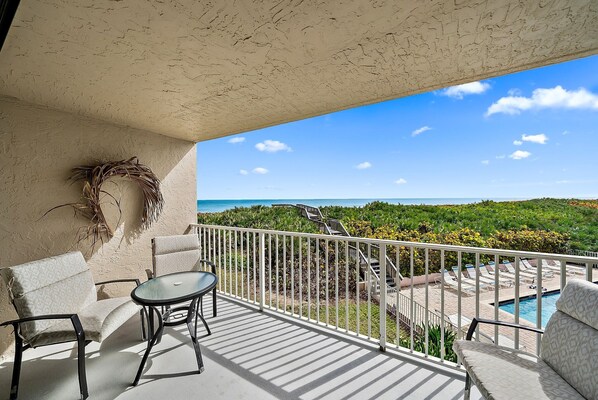 A balcony with a view of a pool and a beach.