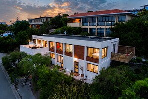 Ein modernes, zweistöckiges Haus mit flachem Dach, großen Fenstern und einem Balkon.