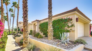 A residential building with a paved walkway, palm trees, and a variety of plants. - Community Pools & Golf Views: Palm Desert Condo! (Palm Desert)