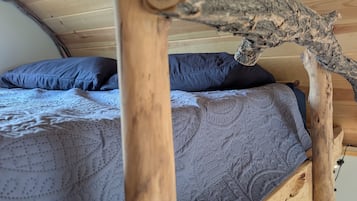 Een stapelbed met een houten hoofdbord en een matras met een gestreept hoes.