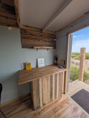 Un comptoir d’accueil en bois, doté d’un tableau blanc, d’une boîte jaune et d’un extincteur.