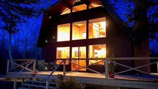 Une cabane en bois à deux étages, dotée d’un balcon et d’un escalier menant à l’entrée.
