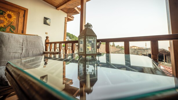 Une table à plateau en verre, agrémentée d’une lanterne et d’une balustrade en bois, et offrant une vue sur l’extérieur.