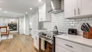 Una cocina moderna con alacenas blancas, estufa de acero inoxidable y salpicadero de azulejos.
