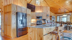 Une cuisine spacieuse dotée de meubles en bois, d’appareils électroménagers en acier inoxydable et d’un grand îlot central avec des tabourets de bar.