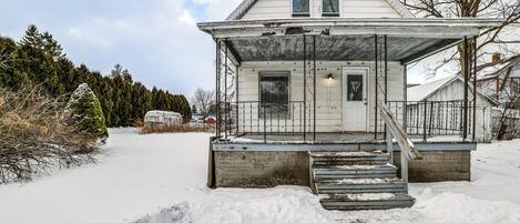 A white house with a porch and steps leading to the front door.