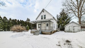 A two-story house with a porch and a small shed in a snowy setting. - Near Hiking & Skiing: Cozy Home in Cortland! (Cortland)