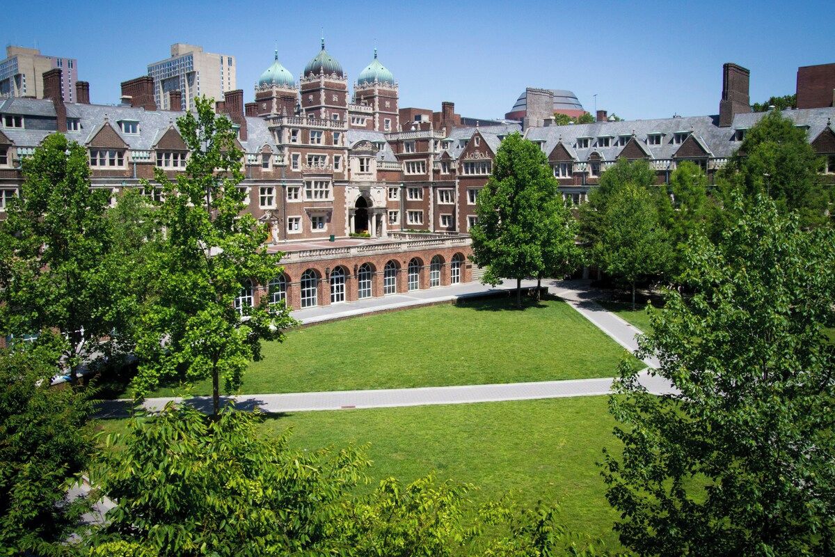 A large, historic building with a central courtyard surrounded by trees.