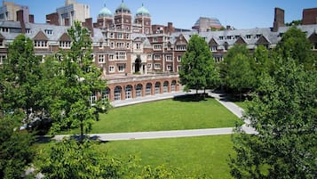 A large, historic building with a central courtyard surrounded by trees.