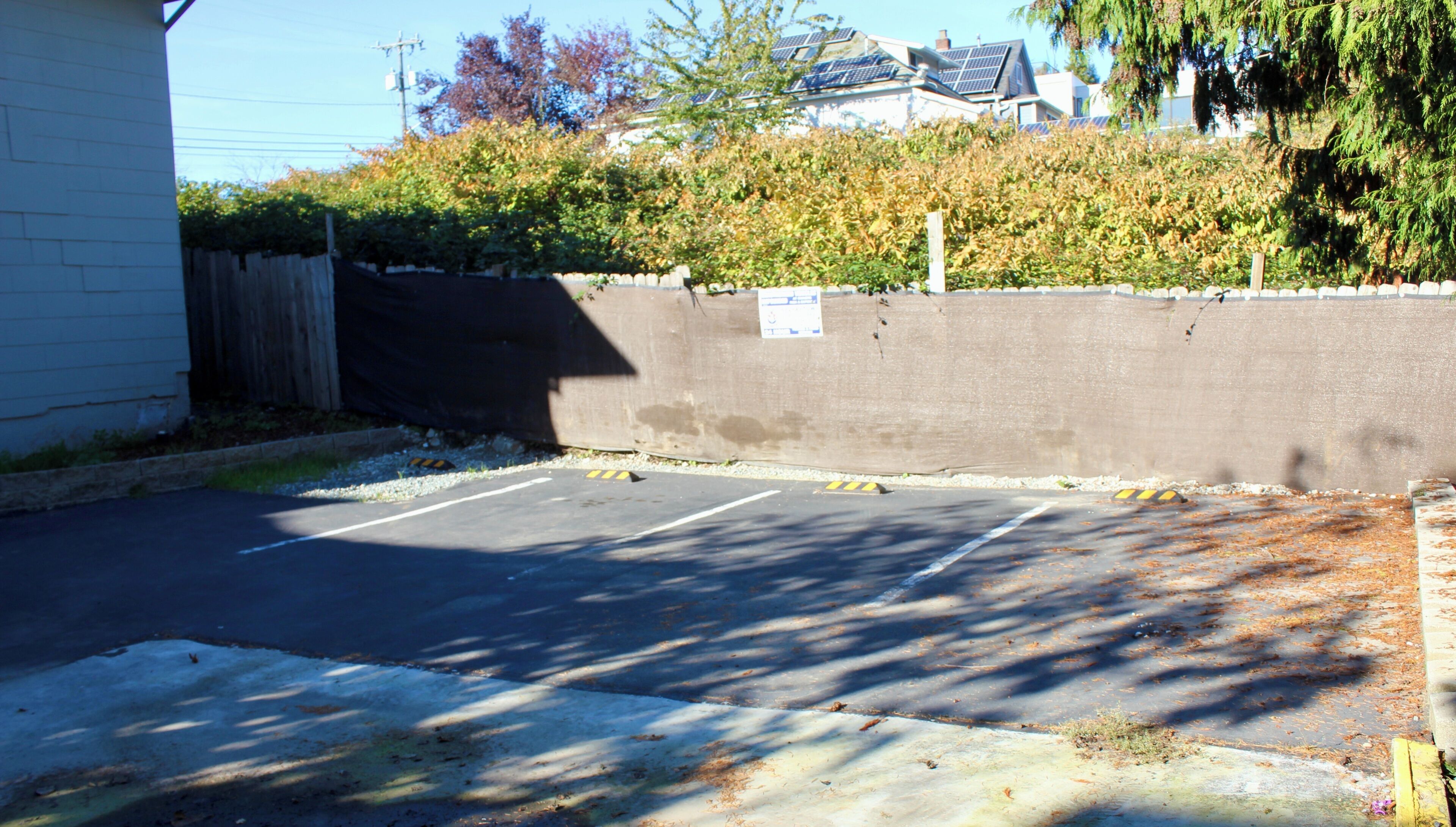Un parking délimité par un mur en béton et une clôture en bois.