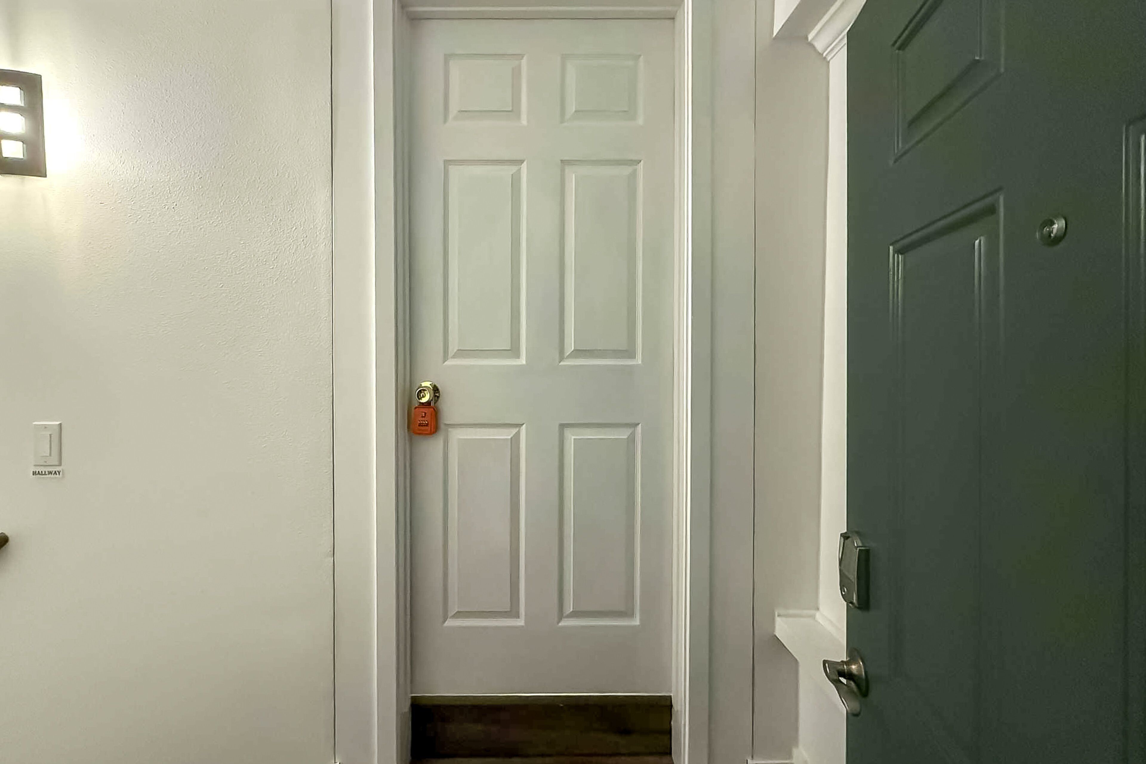 A white door with a small window, a green door, and a doormat.