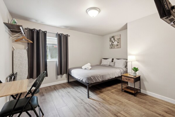 Une chambre à coucher avec un lit, une table de chevet, une lampe et une fenêtre avec des rideaux.