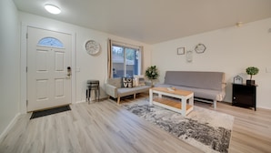 Een woonkamer met een bank, salontafel en een deur met raam.